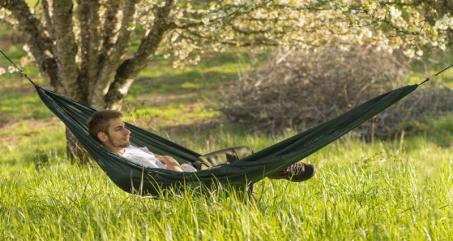 Young country farm man in his 20s laying in a hammock outside