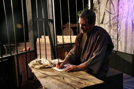 Paul is writing his epistles in the prison cell in this church production